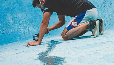 Technician applying sealant to repair a pool leak during professional service by Commercial Pool Kings.